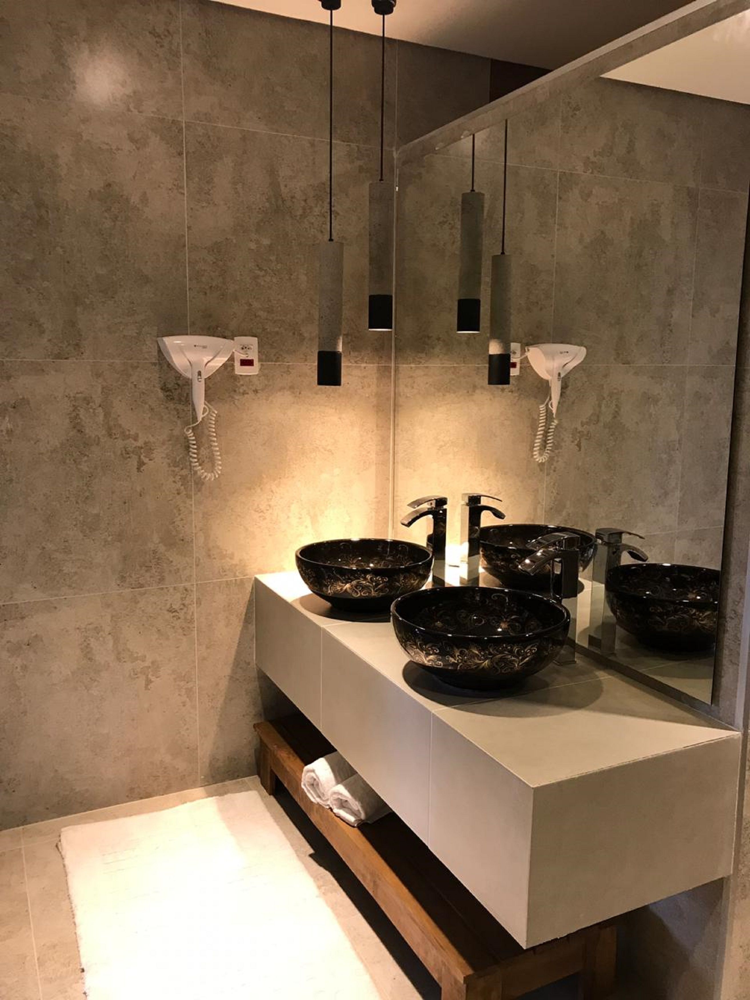 Un baño moderno con un espejo grande, dos lavamanos tipo recipiente negros y un mueble de tocador blanco.