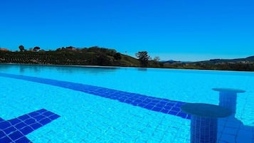Piscina externa, piscina infinita, guarda-sóis, espreguiçadeiras