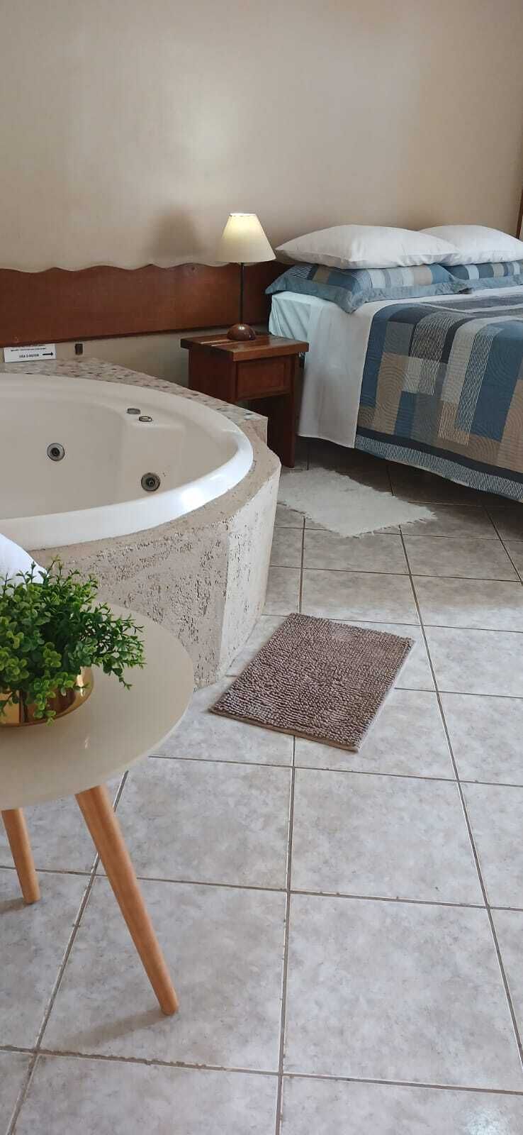 Una camera da letto con una vasca da bagno grande, un comodino con una lampada e un letto con copriletto.