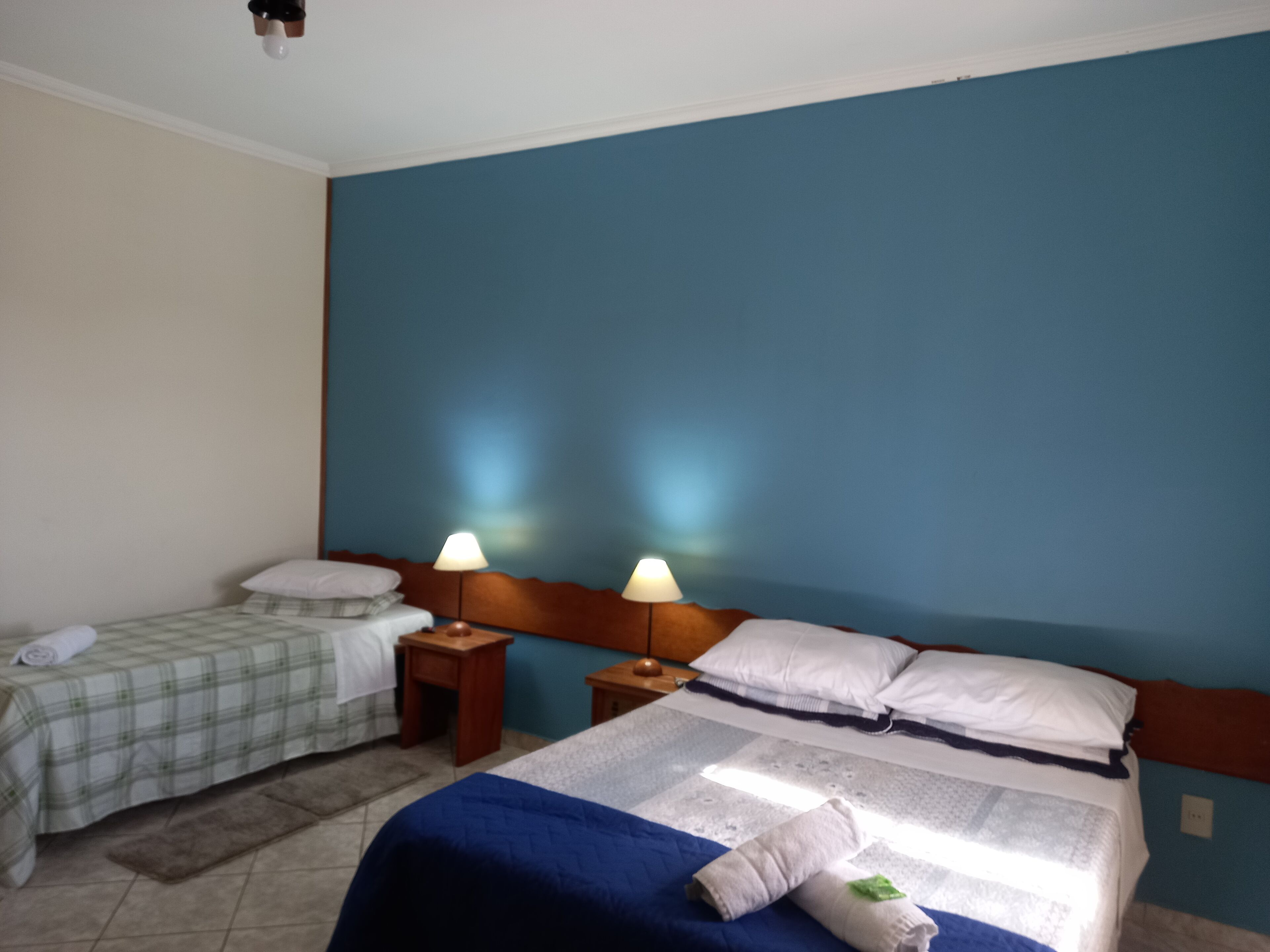 A hotel room with two beds, a blue wall, and a wooden headboard.