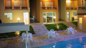 A hotel with multiple balconies, a swimming pool, and outdoor seating. - Miragem Chales (Serra Negra)