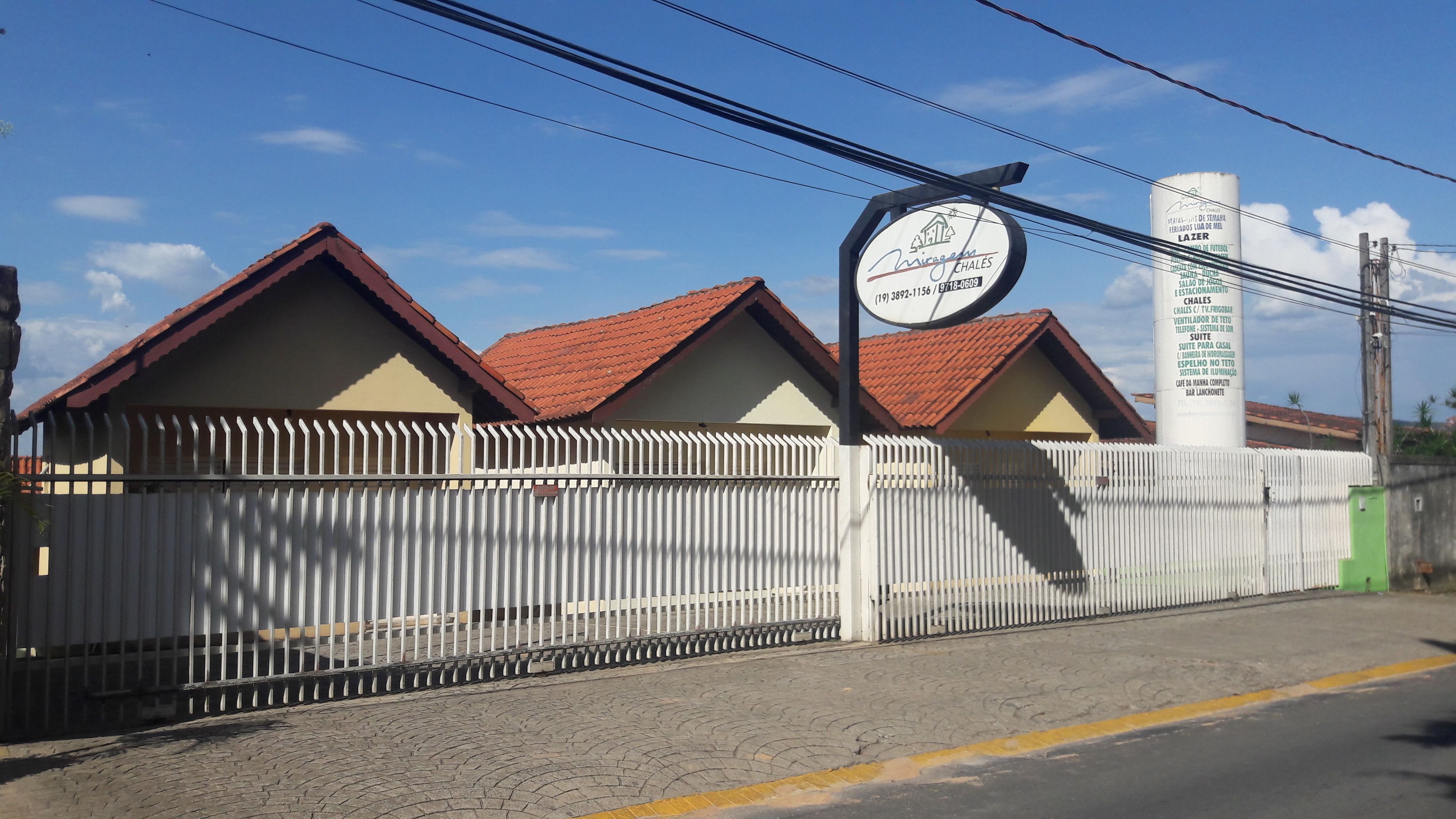 A fenced property with multiple buildings, a signboard, and a utility pole.