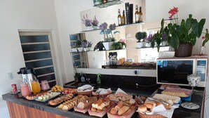A buffet counter with various food items, a coffee machine, and a refrigerator. - Miragem Chales (Serra Negra)