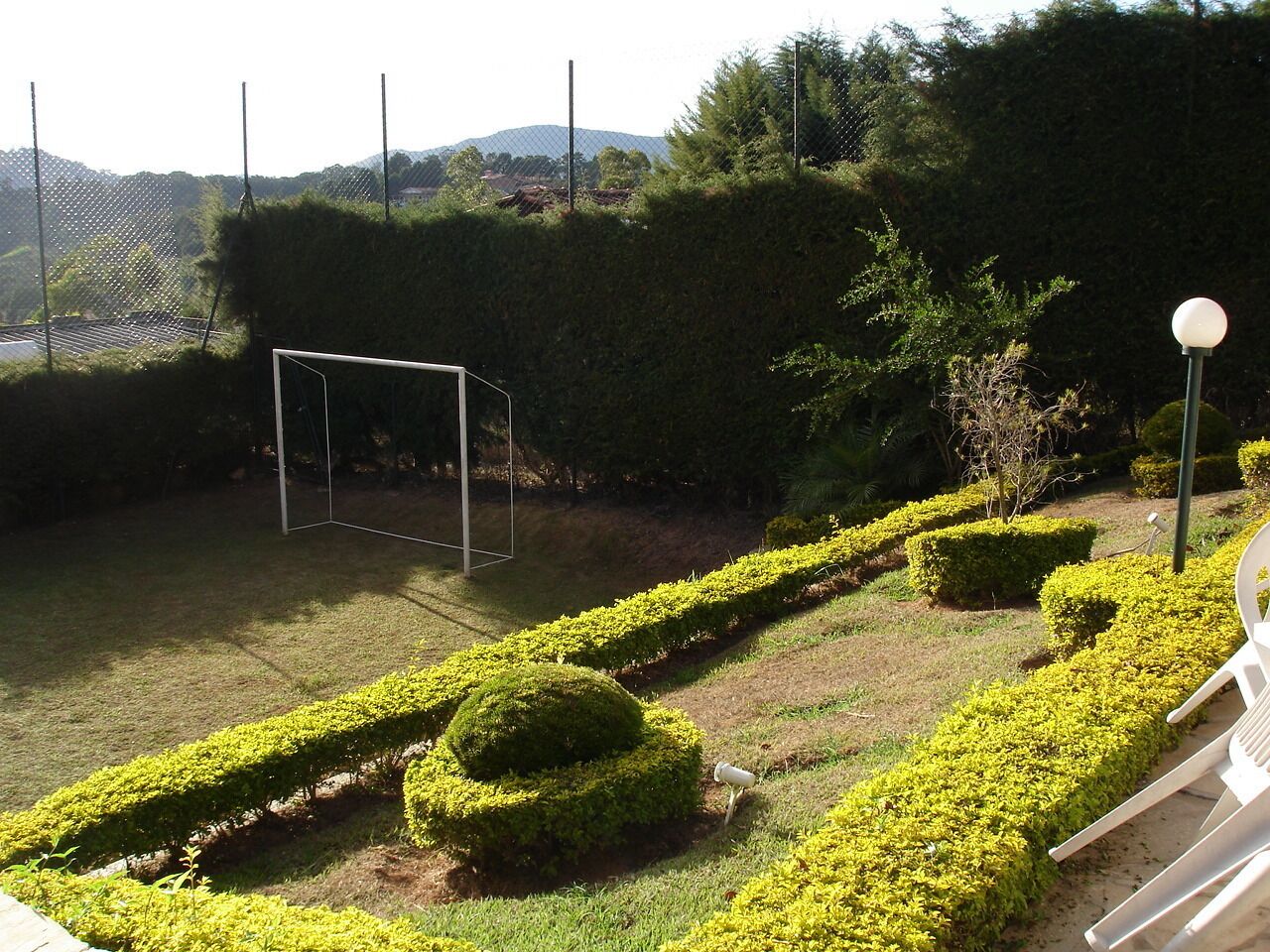 Un jardín bien cuidado con setos recortados, un arco de fútbol y un poste de luz.
