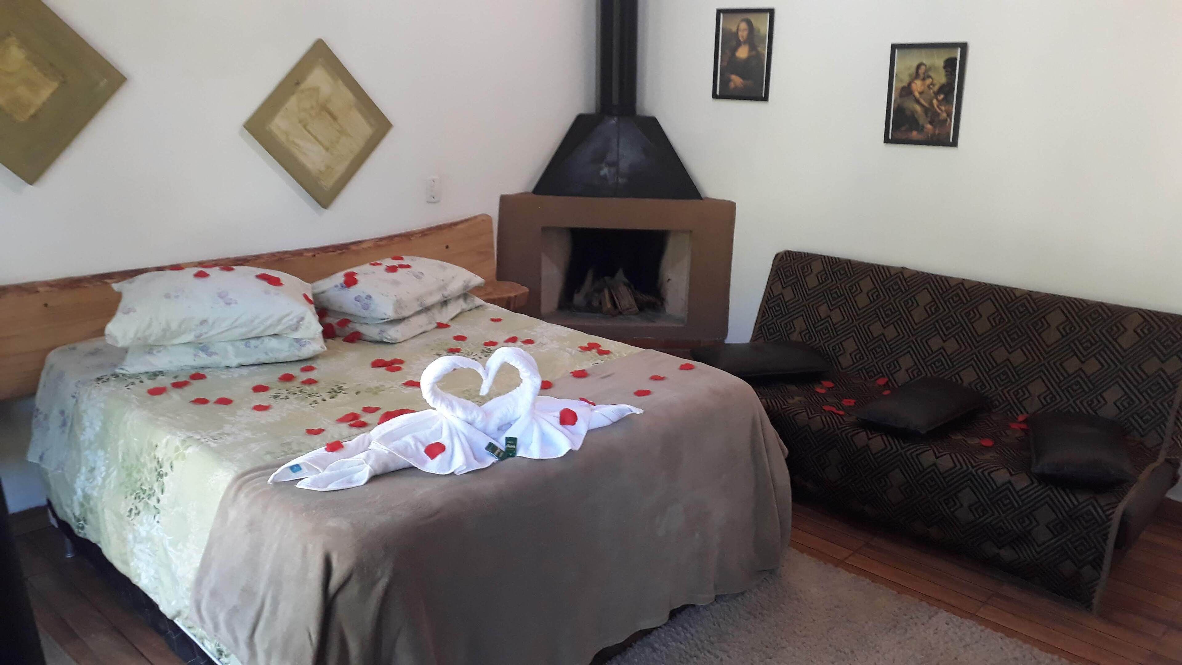 A bedroom with a bed, a sofa, a fireplace, and wall art.