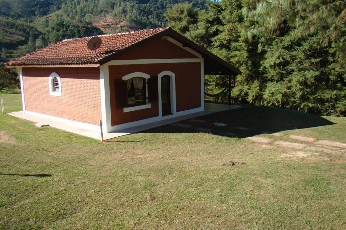 A small, single-story brick building with a sloped roof, a satellite dish, and a small window.