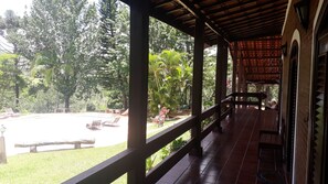 Un espacio al aire libre cubierto con piscina, sillas de descanso y una terraza de madera.