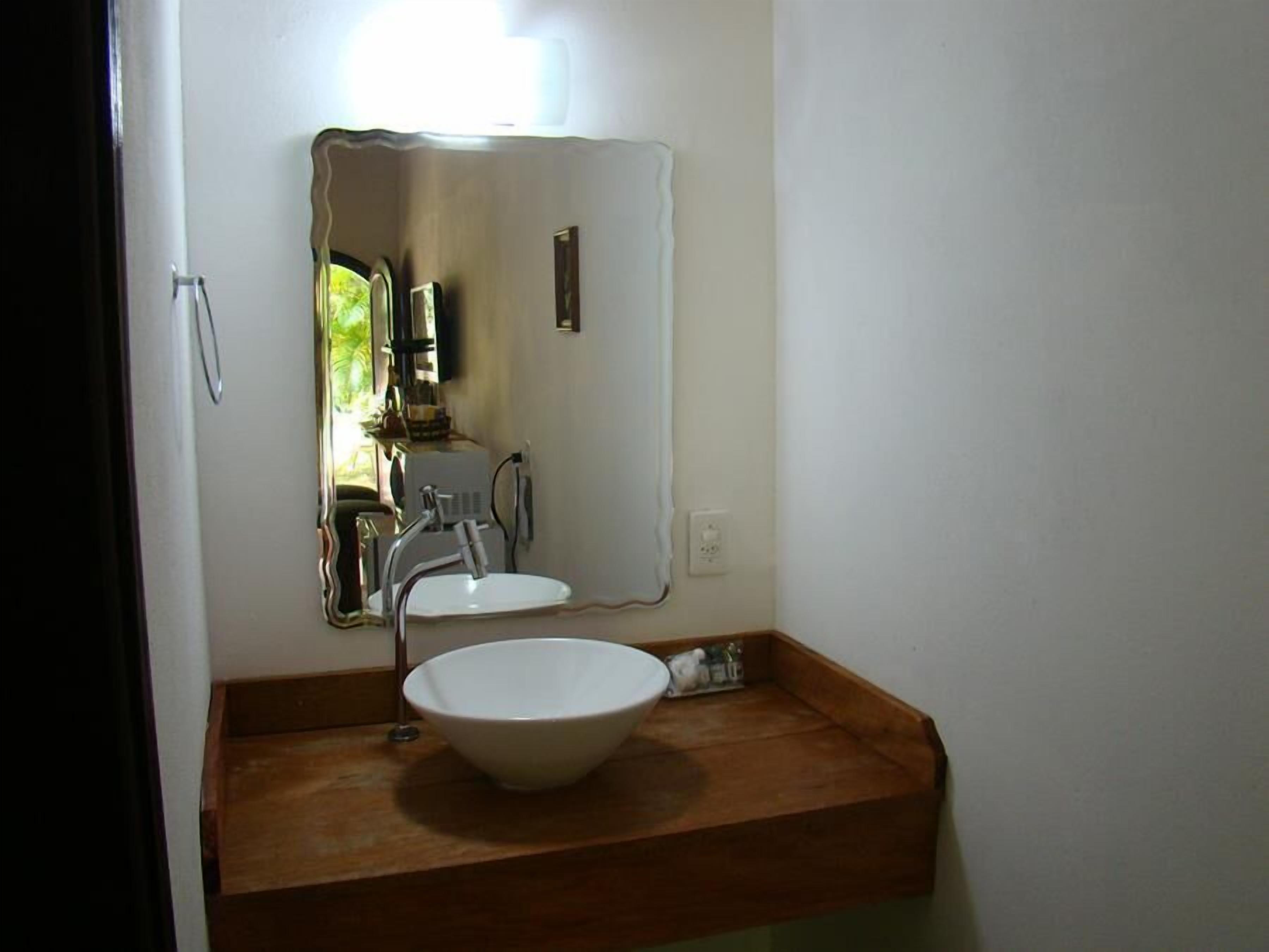 A bathroom with a wooden vanity, a white sink, and a mirror.