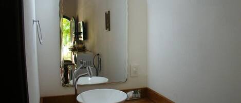 A bathroom with a wooden vanity, a white sink, and a mirror.