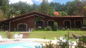 Un edificio de dos plantas con piscina, mobiliario exterior y jardín.