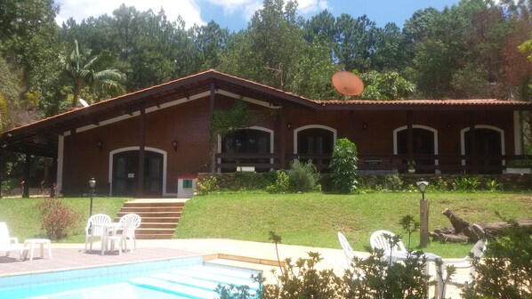 A two-story building with a swimming pool, outdoor seating, and a garden. - Refúgio Serra Negra (Serra Negra)