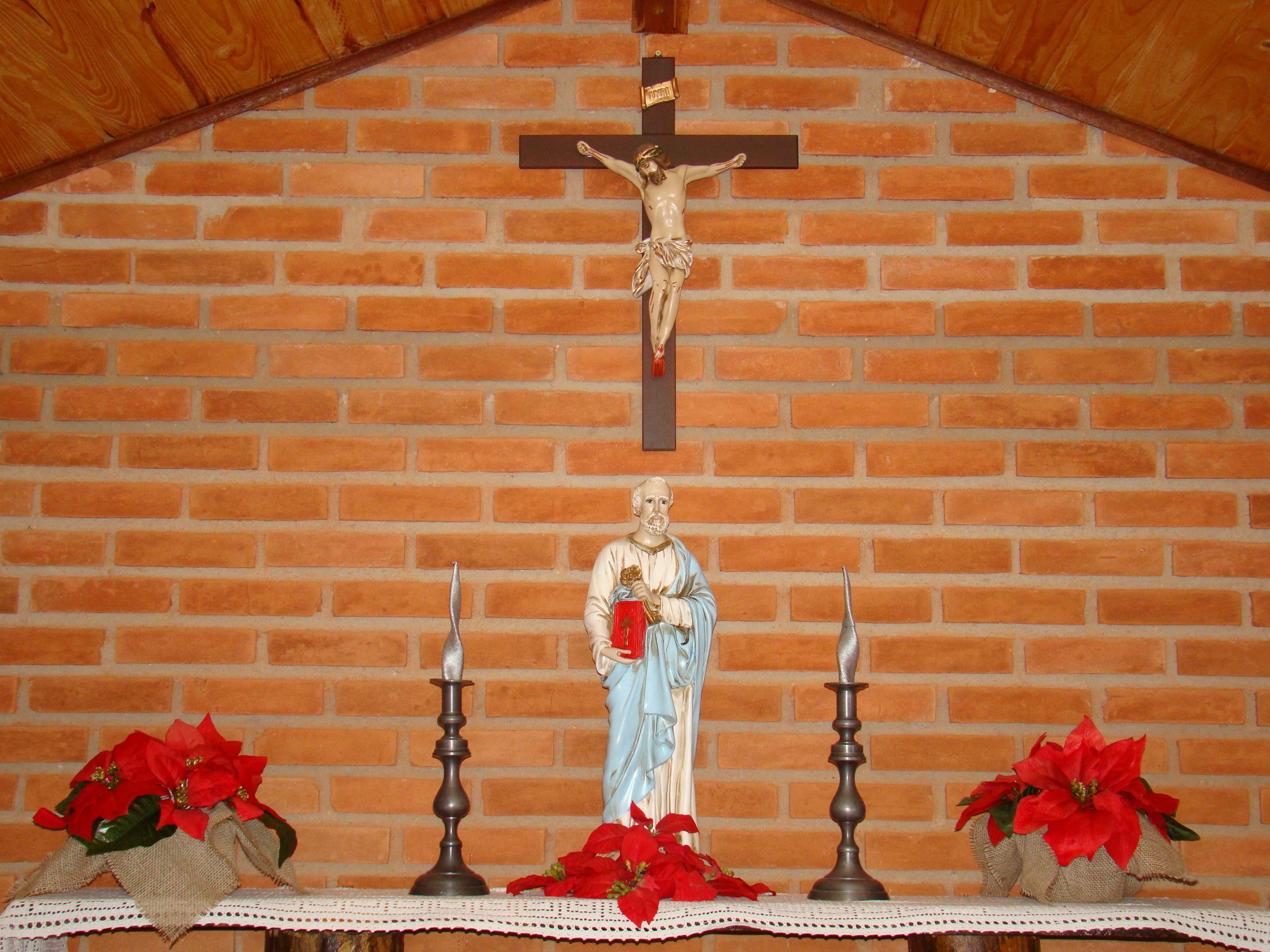 Un muro de ladrillo con una cruz y una estatua de una figura religiosa.