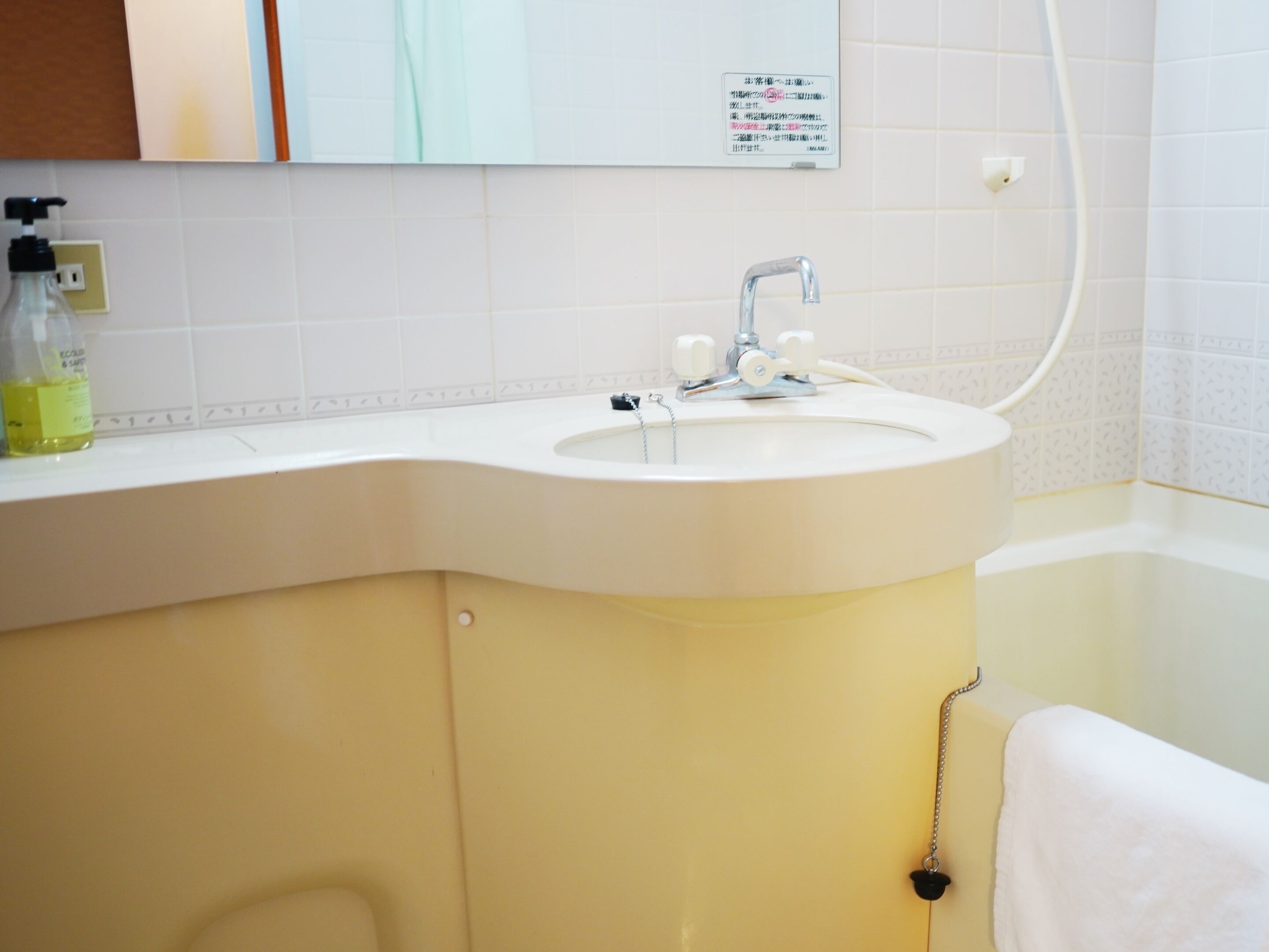A bathroom with a white sink, a mirror, and a towel rack.