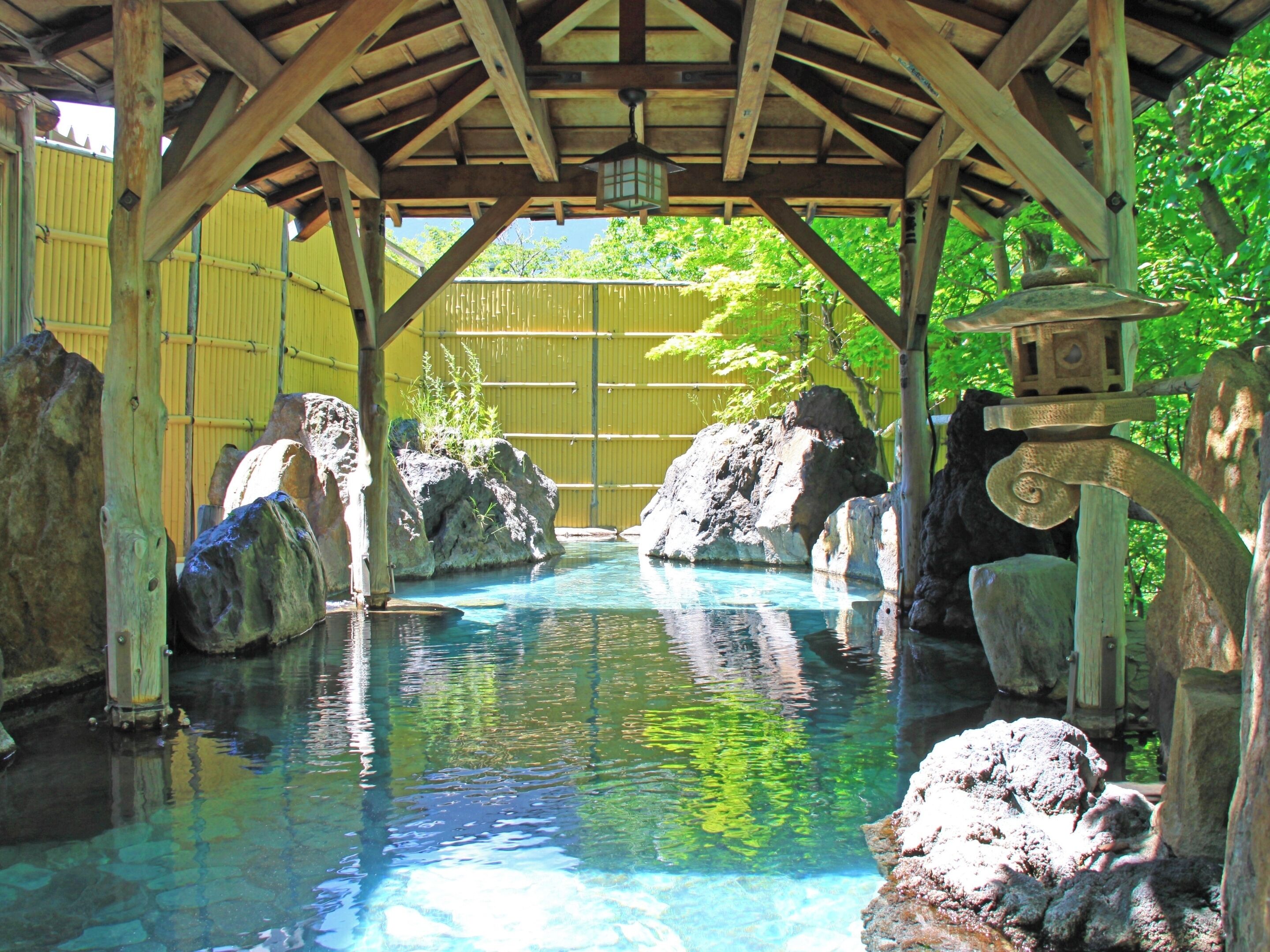 Una estructura de madera con piscina, rocas y una fuente.