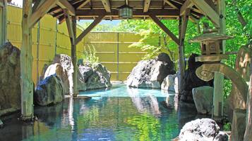 A wooden structure with a pool, rocks, and a water feature.