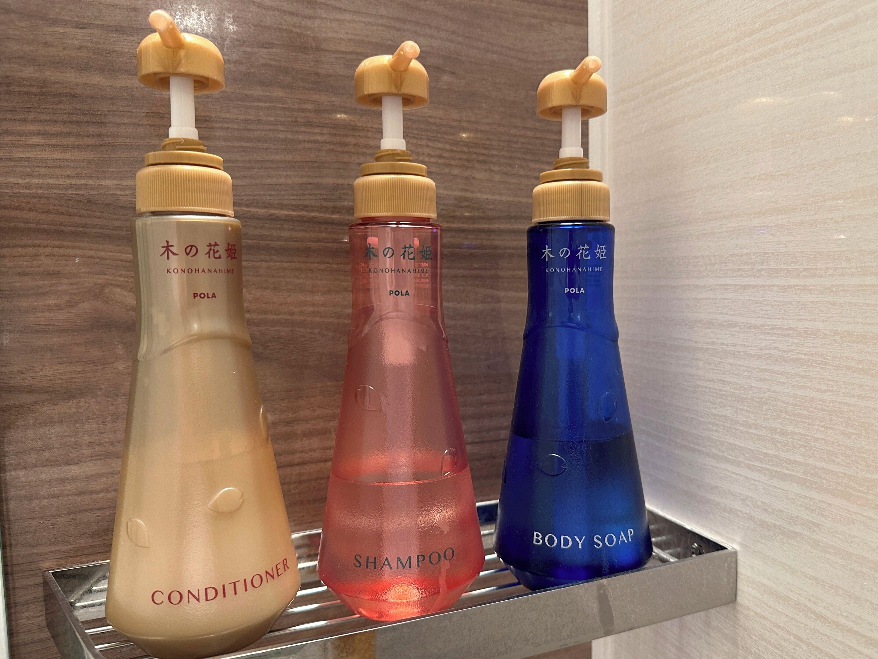 Three bottles of KonohanaHime products: conditioner, shampoo, and body soap, arranged on a metal shelf.