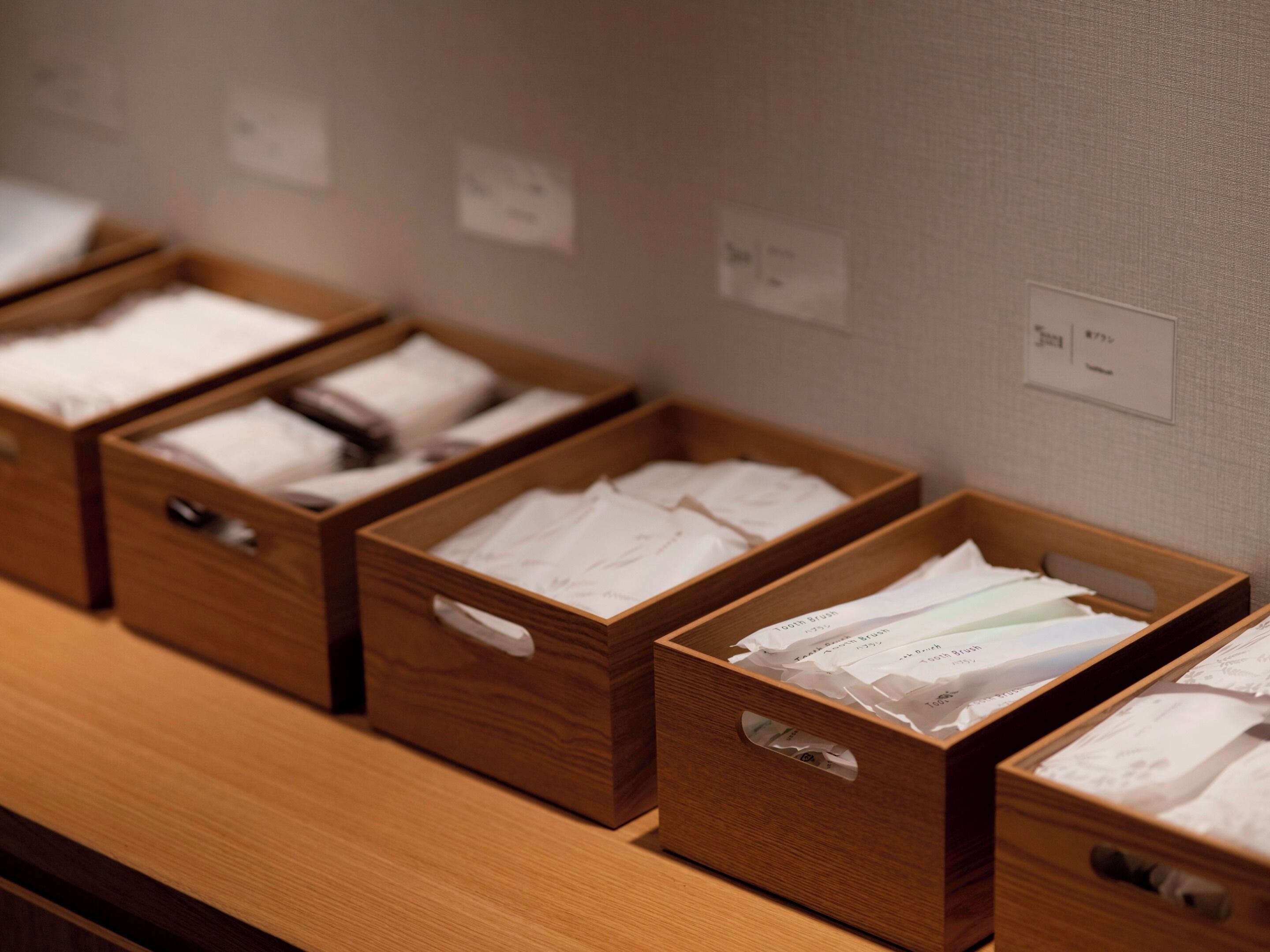 Wooden storage boxes with papers on a wooden shelf.