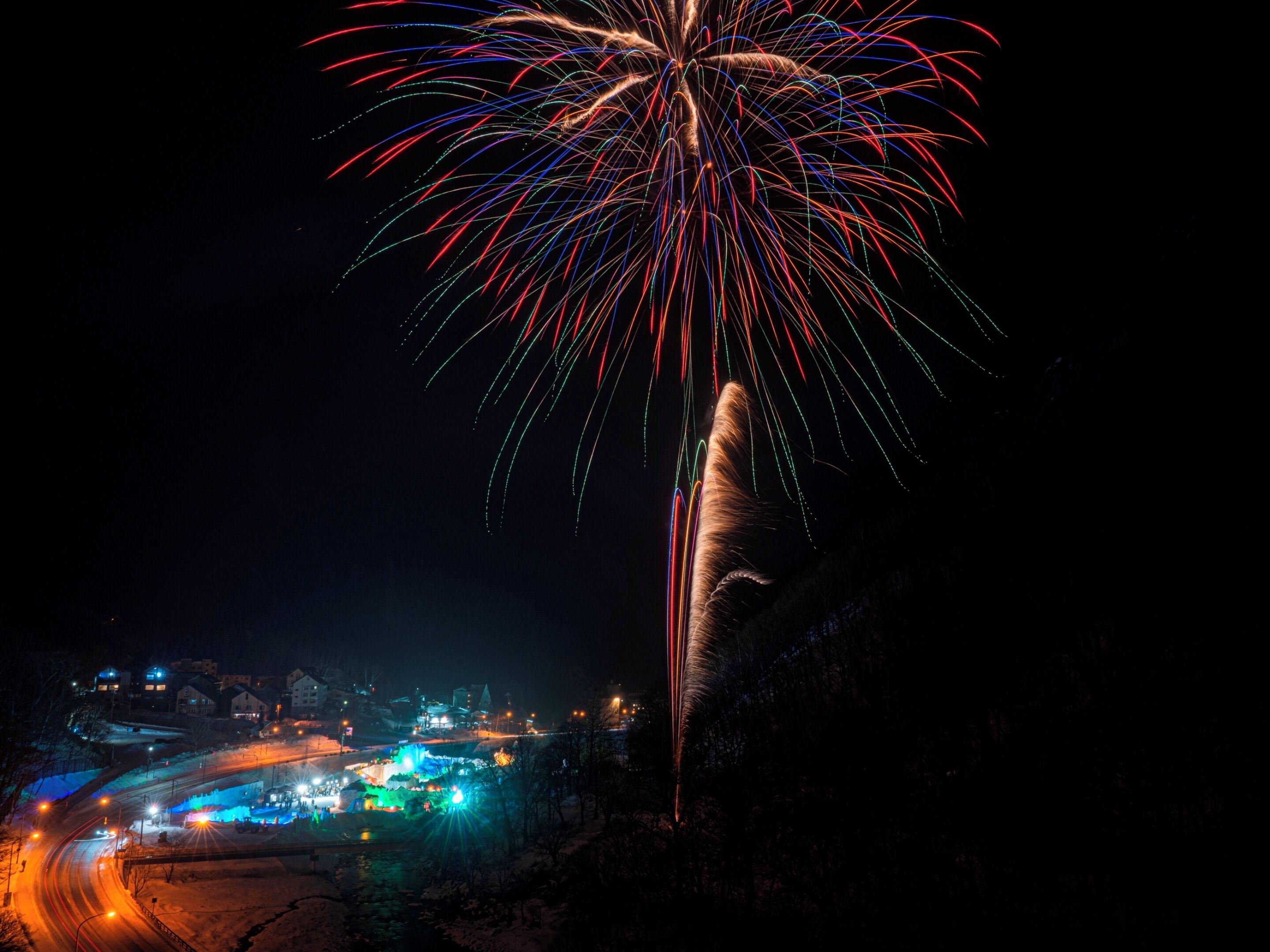 A nighttime view of a town with a prominent display of fireworks.