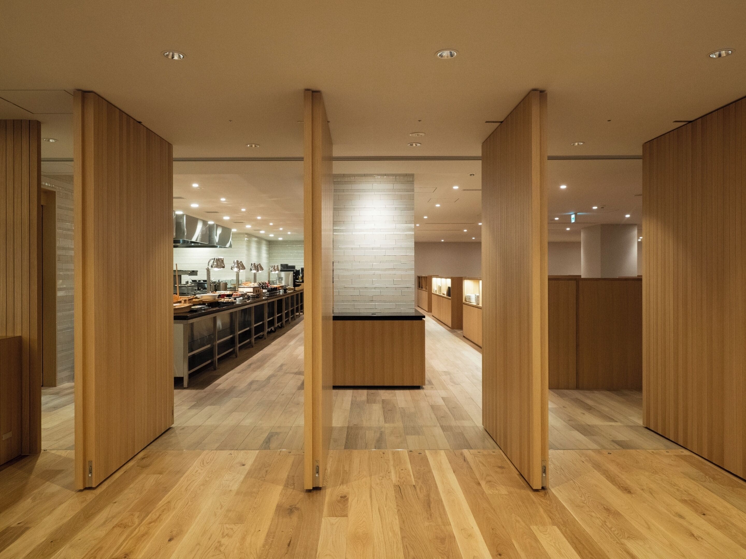 A modern interior with wooden paneling, a central island, and a kitchen area with appliances and counter space.