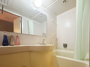 A bathroom with a white bathtub, a sink with a mirror above it, and three bottles of soap on the counter. - Sounkaku  (Kamikawa)