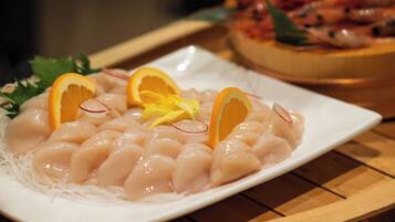 A plate of sashimi with orange slices and radish on a white plate.
