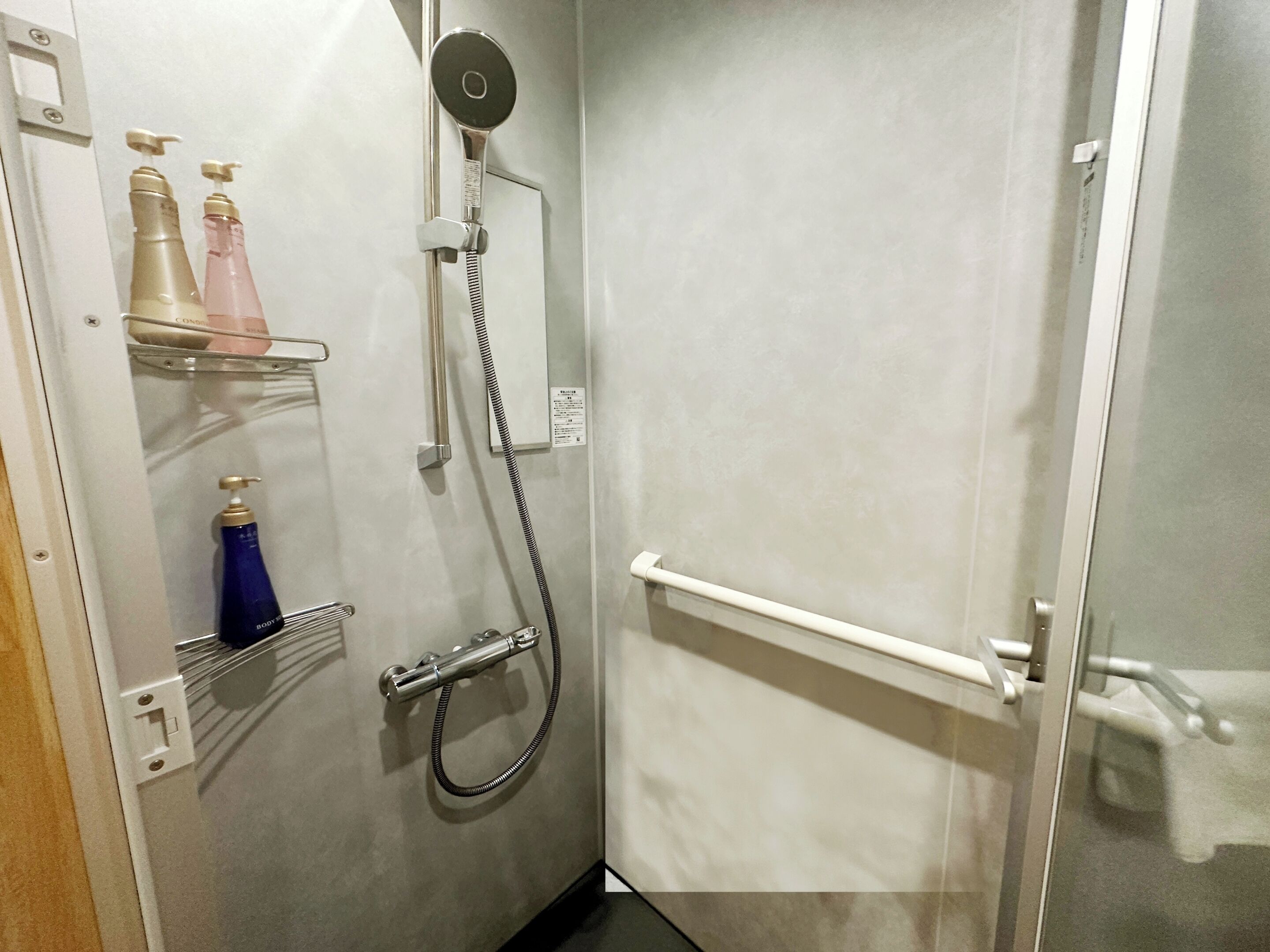 Ein Badezimmer mit Dusche, einem Handtrockner und einem Ablagefach für Toilettenartikel.