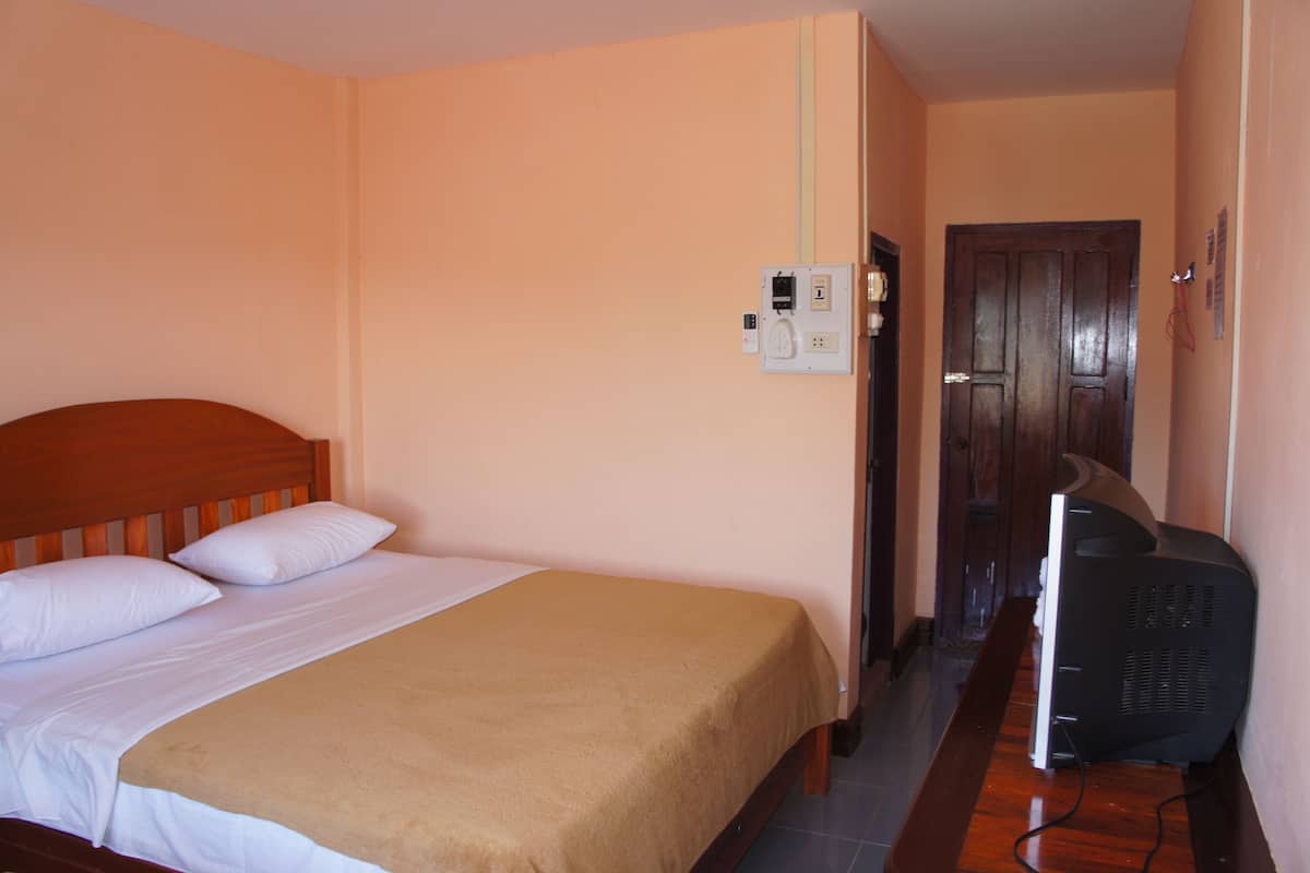 A hotel room with a bed, a television, and a door.