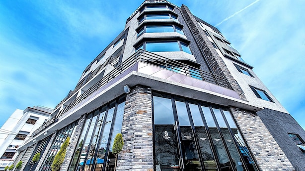 Un hotel moderno con entrada en esquina, ventanas amplias y fachada de piedra.