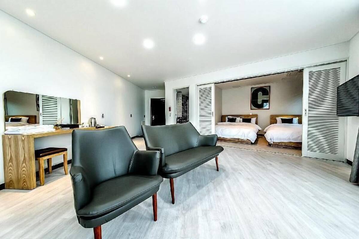 Una habitación de hotel moderna con un sofá, un escritorio y dos camas.
