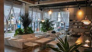 Un moderno espacio lounge con asientos, plantas y una zona de bar con estanterías.
