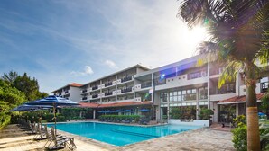A hotel with a swimming pool, sun loungers, and umbrellas. - Iriomote Hotel by Hoshino Resorts (Taketomi)