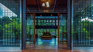 A spacious lobby with a large central fountain, glass walls, and a tiled floor. - Iriomote Hotel by Hoshino Resorts (Taketomi)