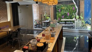 A modern hotel lobby with a bar area, seating, and a view of a lush indoor garden. - Silom convent garden (Bangkok)