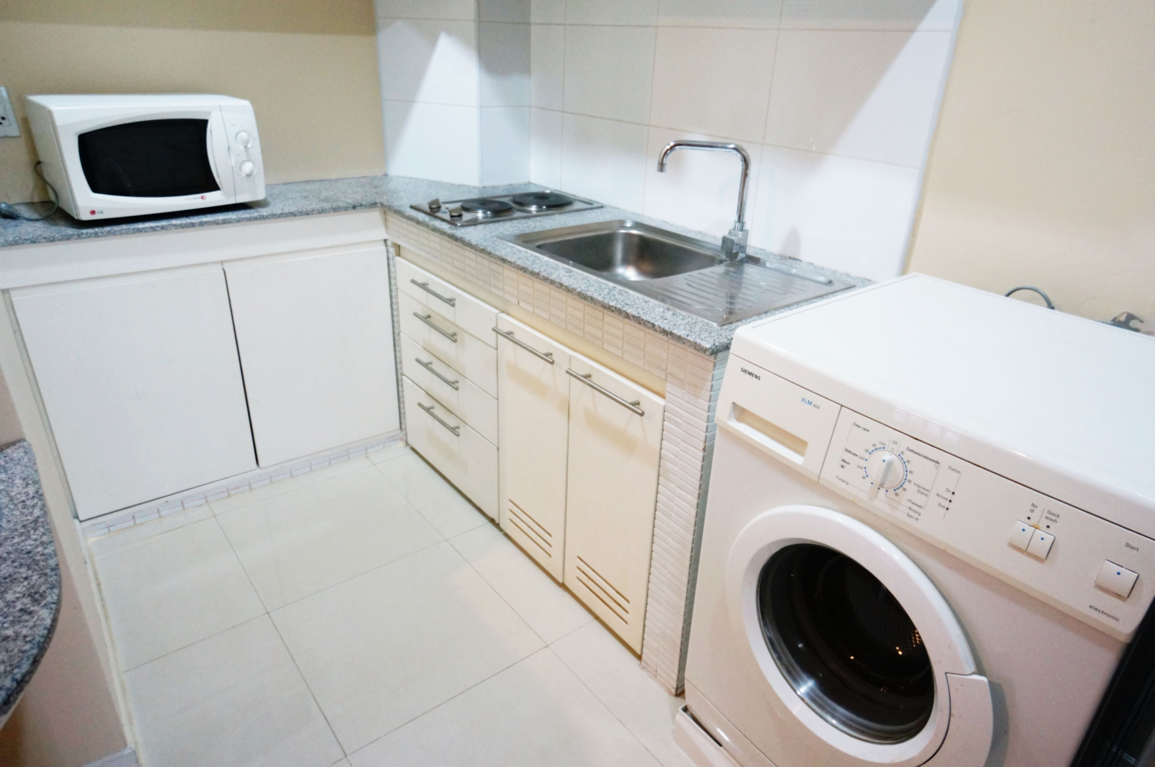 Una cocina compacta con microondas, lavabo y lavadora.