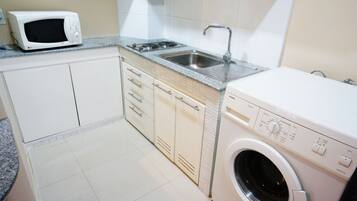 Una cocina compacta con microondas, lavabo y lavadora.