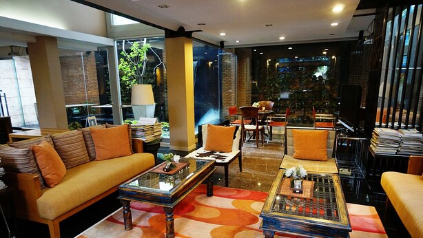 A modern hotel lobby with a sofa, two coffee tables, and a TV. - Silom convent garden (Bangkok)
