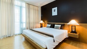 A modern hotel room with a large bed, two bedside lamps, a headboard, and a framed picture on the wall. - Silom convent garden (Bangkok)