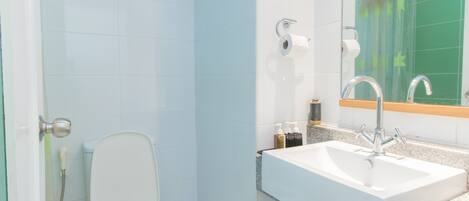 A bathroom with a toilet, sink, and shower.