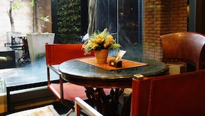 A dining area with a round table, red chairs, and a wicker chair. - Silom convent garden (Bangkok)