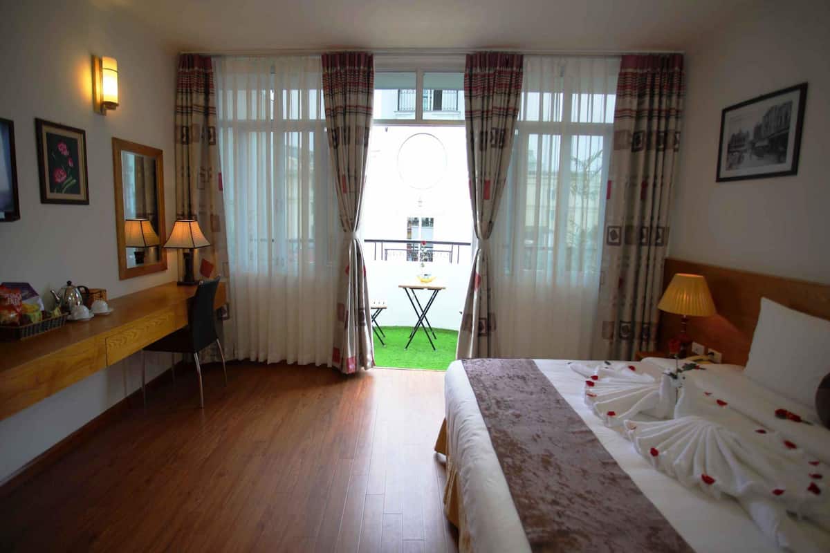 Habitació d'hotel amb llit, escriptori, cadira i un balcó amb taula i seients.
