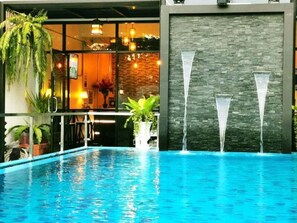 A modern indoor pool with clear water, surrounded by potted plants and a stone wall with water features. - Beach Gallery House (Pattaya)