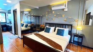 A hotel room with a large bed, a desk, and a chair. There is a wall-mounted air conditioner and a mirror. - Beach Gallery House (Pattaya)