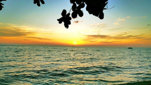 A sunset over the ocean with waves approaching the shore. - Beach Gallery House (Pattaya)
