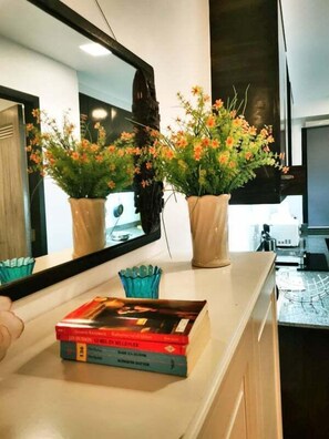Enjoy cooking in this well-equipped kitchen with a large mirror above the countertop and a window with blinds.