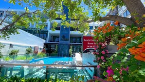 A hotel with a swimming pool, a sign for 'Beach Garden Room for 090 41', and lush greenery. - Beach Gallery House (Pattaya)