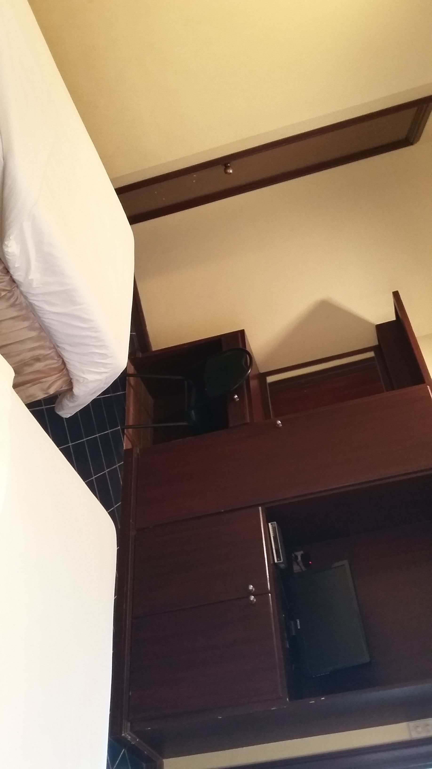 A room with a bed, a small kitchenette, and a dark-colored cabinet.