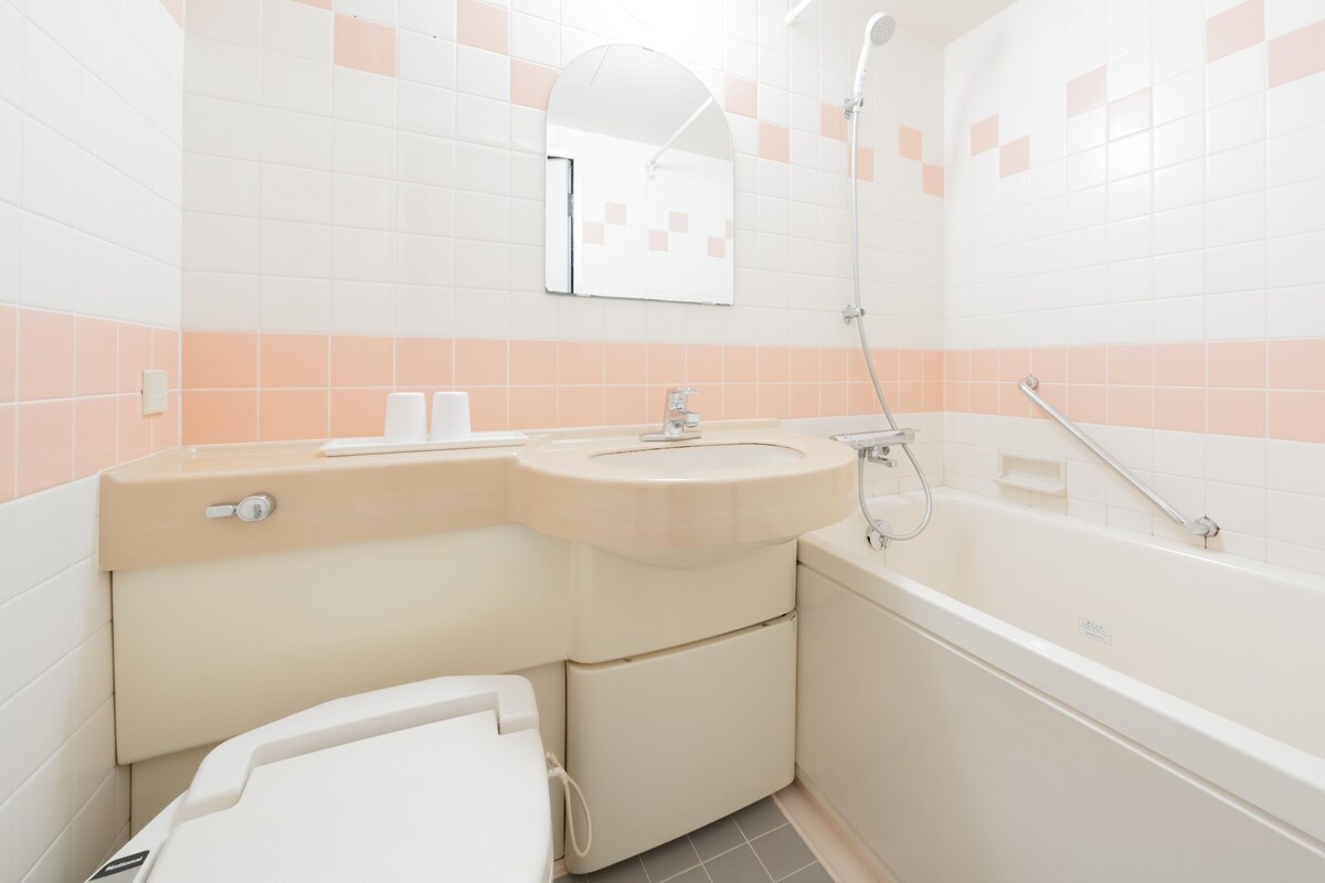 A bathroom with a toilet, sink, mirror, and bathtub.