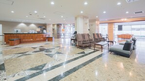 Un vestíbulo amplio con mostrador de recepción, zona de estar y un ventanal con vistas al exterior.