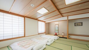 Una habitación japonesa tradicional con suelo de tatami, puertas correderas y un techo bajo con vigas de madera.