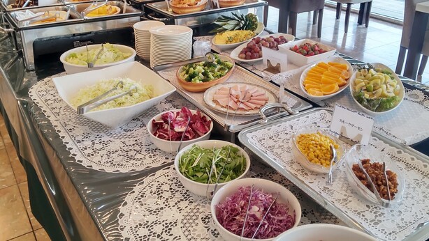 Un bufé con diversos alimentos y vistas del comedor con mesas y sillas.